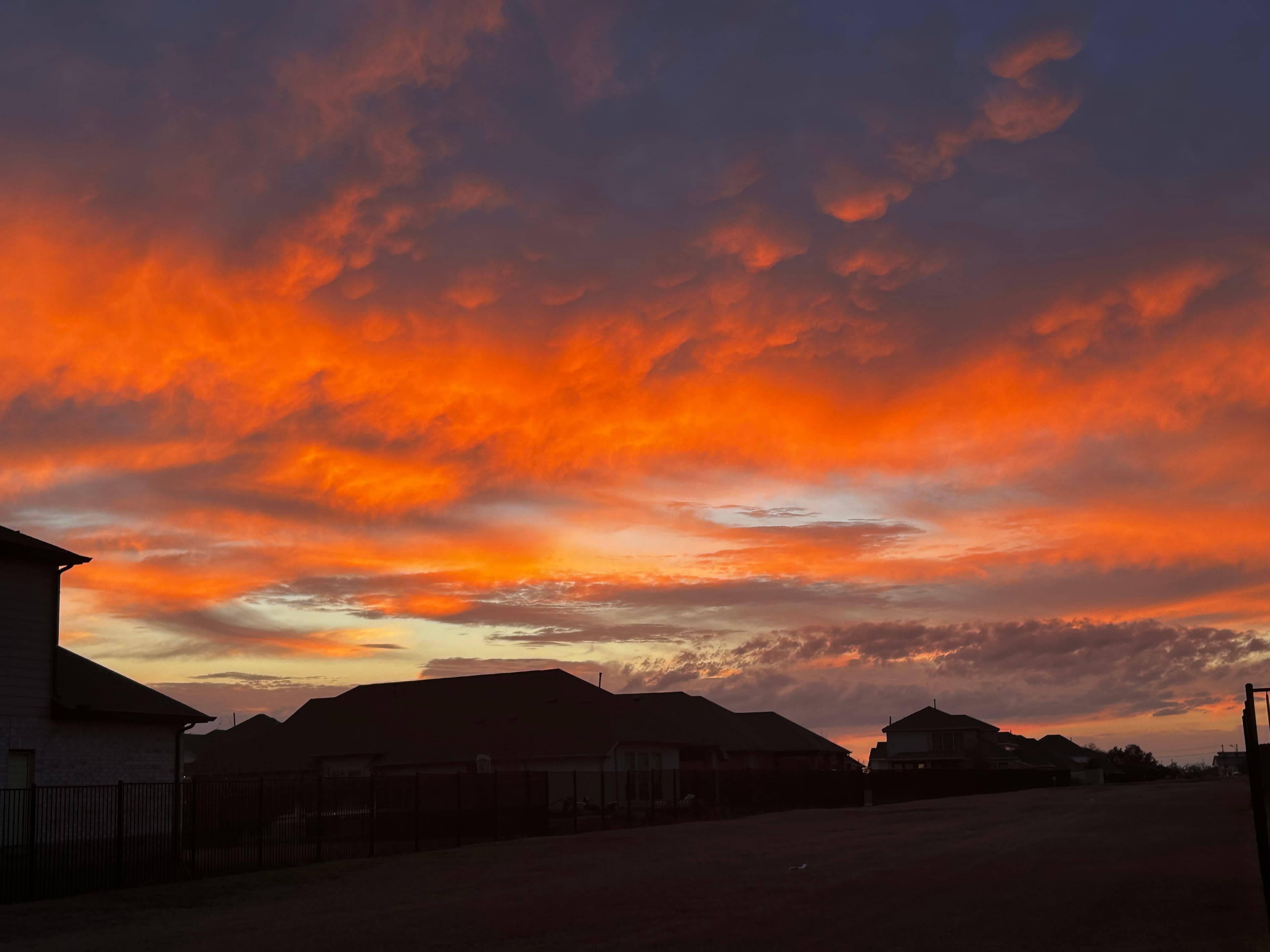 Orange sunset clouds above rooftops, photographed by Anudeep